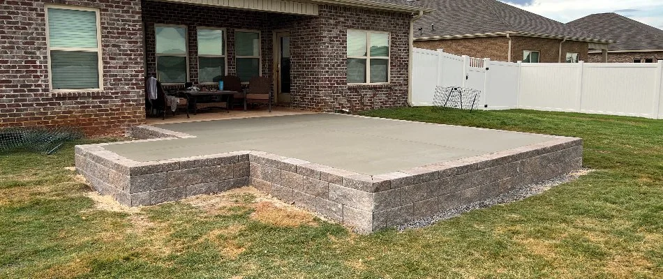 Backyard in Huntsville, AL, with a block retaining wall and patio.