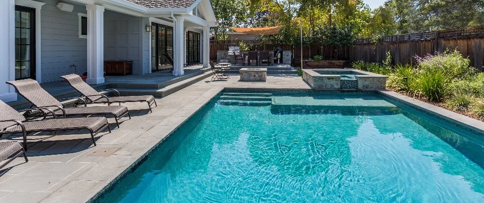 Pool with a spa and lounge chairs in a backyard in Huntsville, AL.