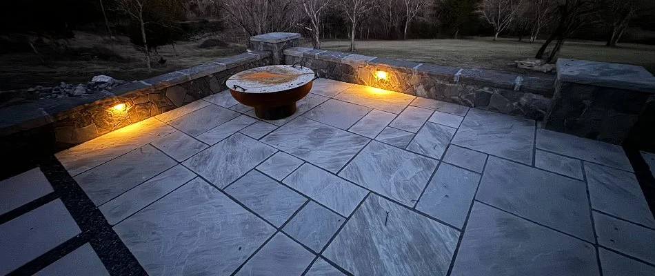 Natural stone patio in Kelso, TN, with seating wall and outdoor lighting.