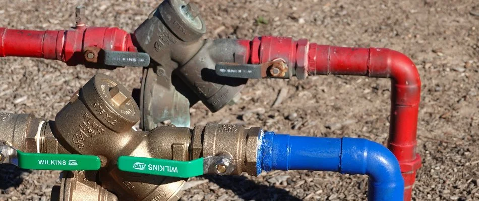 Red and blue irrigation lines with backflow valves in Huntsville, AL.