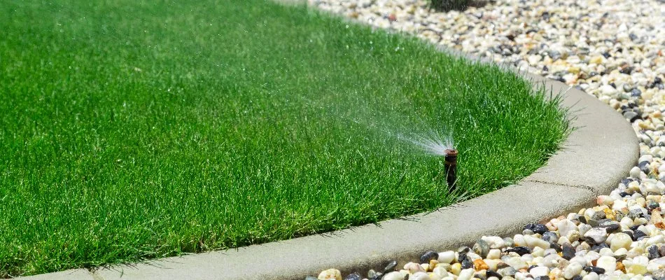 Sprinkler along the edge of a lawn and landscape bed in Hobbs Island, AL.